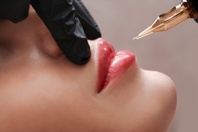 Young woman undergoing procedure of permanent lip makeup in tattoo salon, closeup