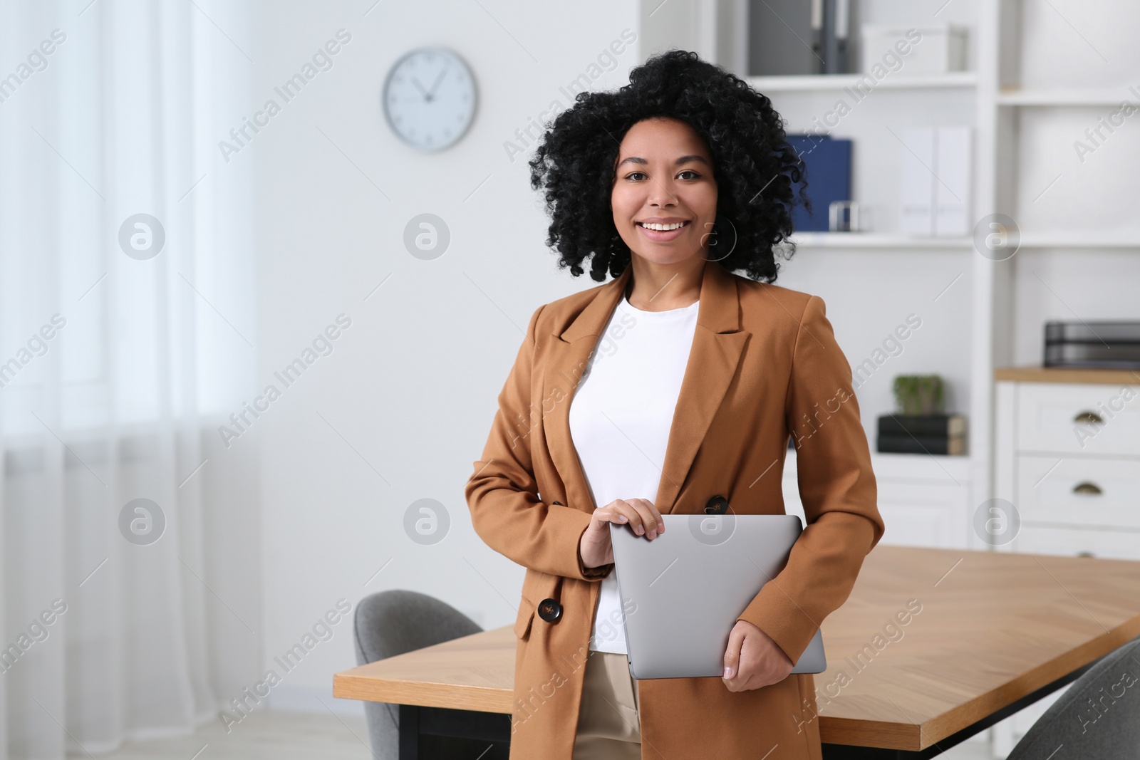 Photo of Smiling young businesswoman with laptop in modern office. Space for text