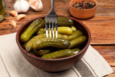 Photo of Eating tasty pickled cucumbers with fork at wooden table