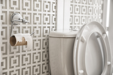 Photo of Toilet and holder with empty paper roll in bathroom