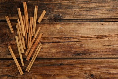 Photo of Aromatic cinnamon sticks on wooden table, flat lay. Space for text