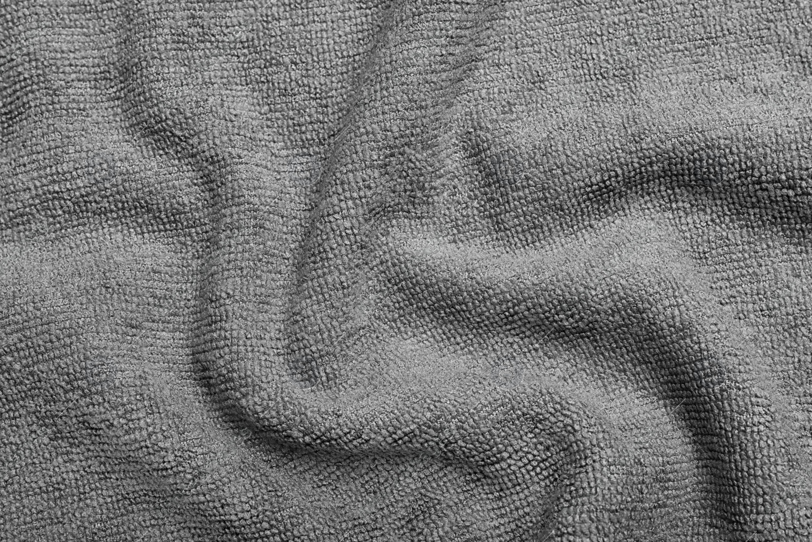 Photo of Crumpled grey microfiber cloth as background, closeup