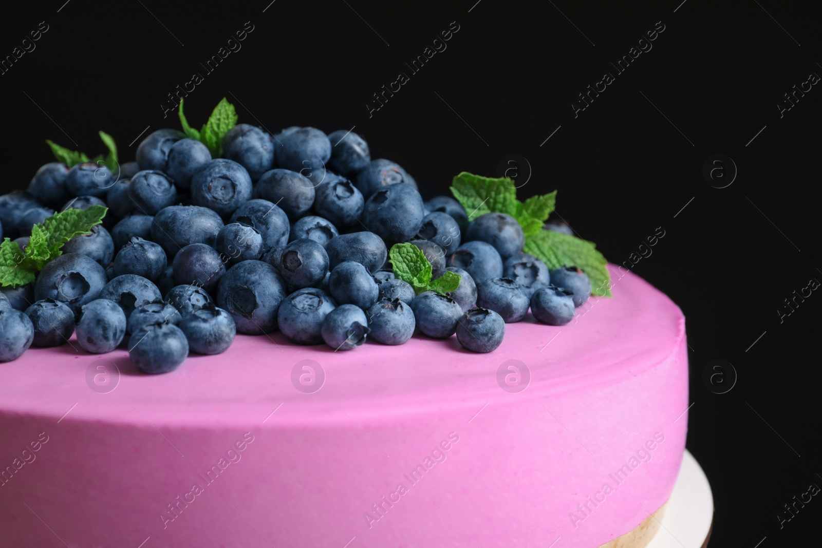 Photo of Tasty cheesecake decorated with fresh blueberries and mint on black background, closeup