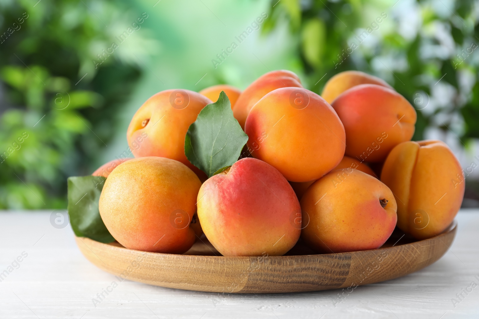 Photo of Many fresh ripe apricots on white table against blurred background