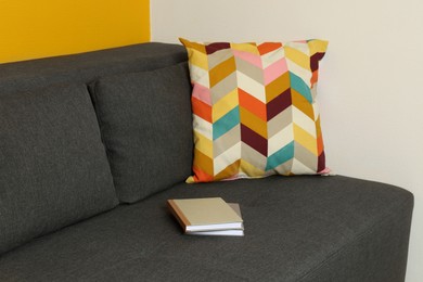 Bright cushion and books on grey sofa in room