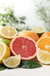 Photo of Different cut and whole citrus fruits on white table, closeup