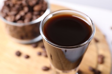 Shot glass of coffee liqueur on blurred background, closeup