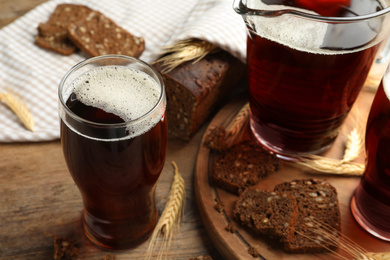 Photo of Delicious kvass, bread and spikes on wooden table