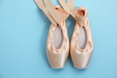 Photo of Ballet shoes. Elegant pointes on light blue background, flat lay. Space for text