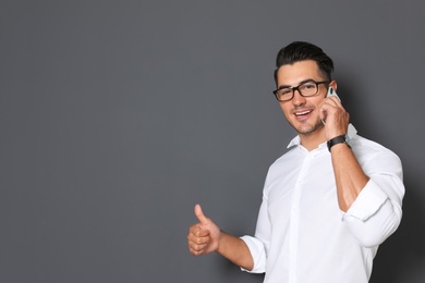 Handsome young man talking on phone against black background. Space for text