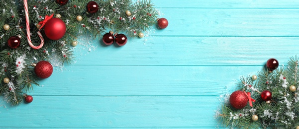 Fir tree branches with Christmas decoration on light blue wooden background, flat lay. Space for text