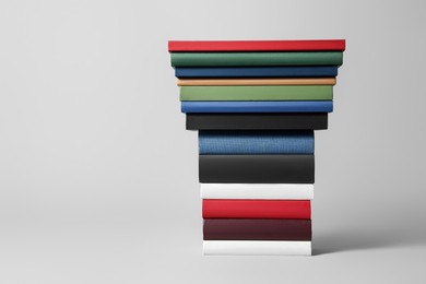 Photo of Stack of different hardcover books on light grey background. Space for text
