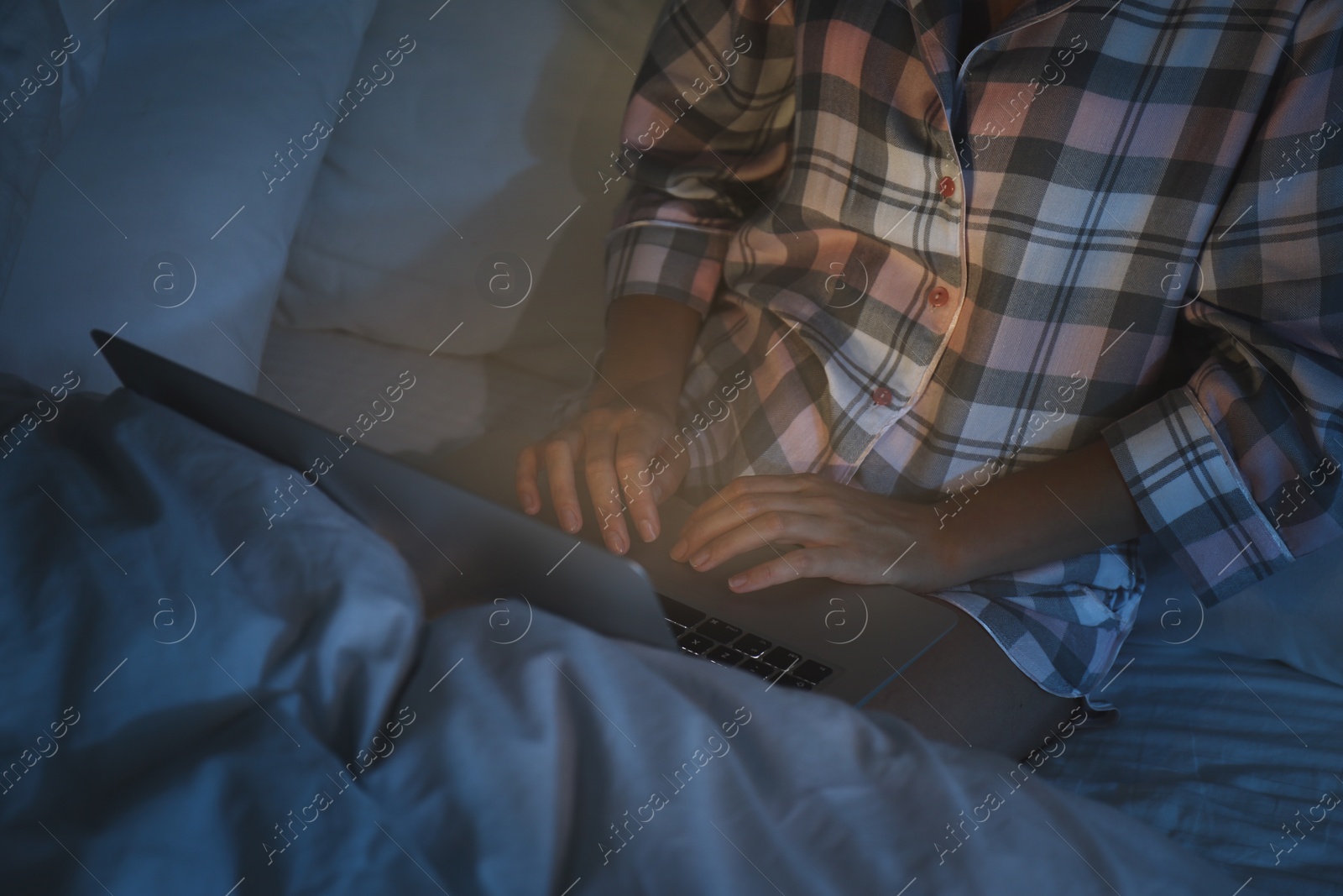 Photo of Woman using laptop in bed at night, closeup. Sleeping disorder problem