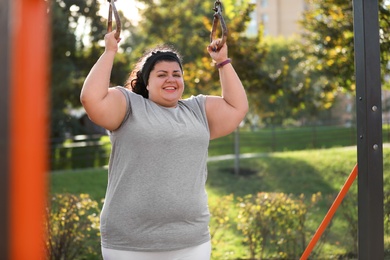 Beautiful overweight woman training on sports ground