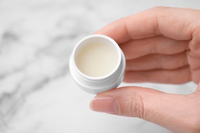 Photo of Woman holding jar of petroleum jelly on light background, closeup