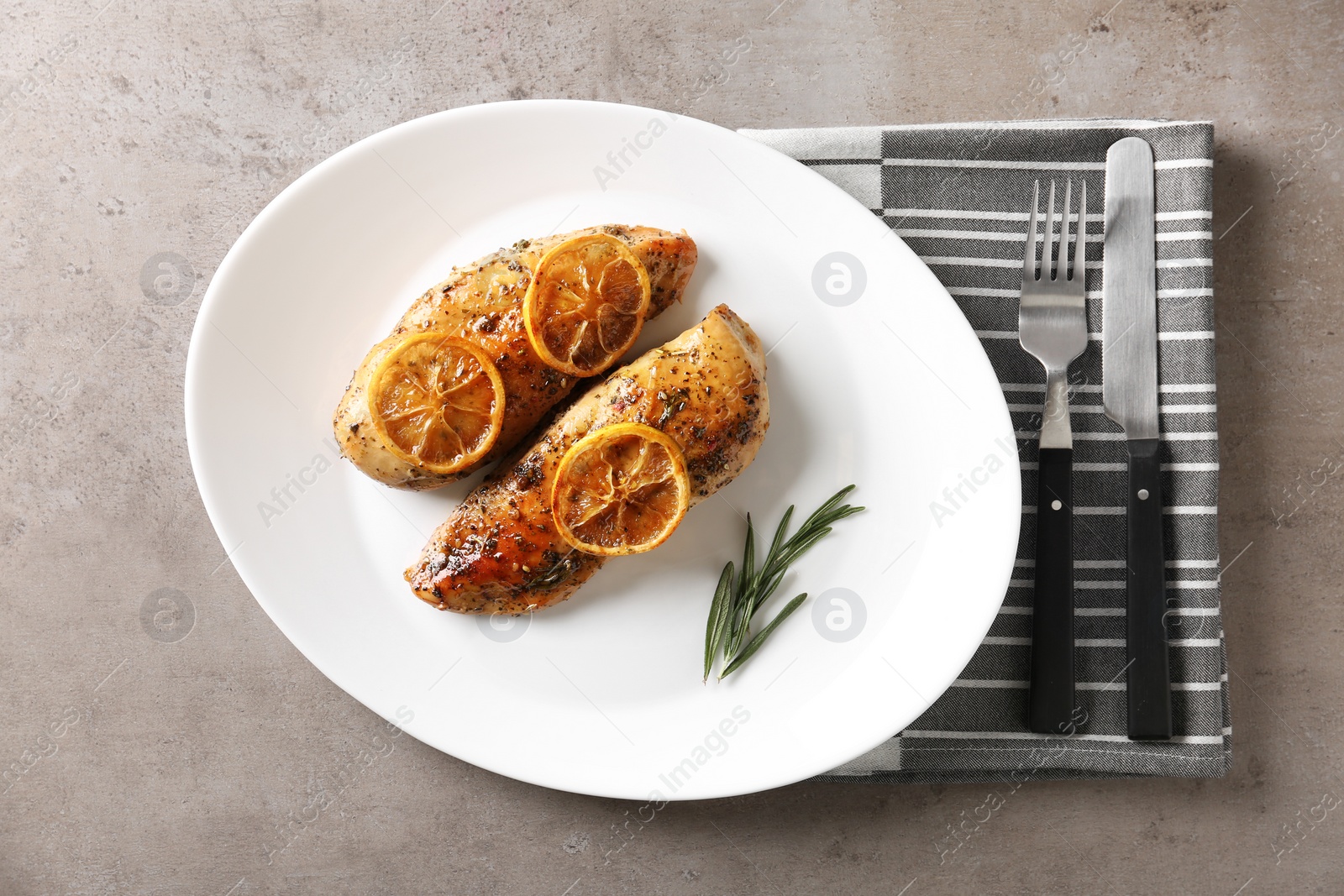 Photo of Delicious lemon chicken served on grey table, flat lay