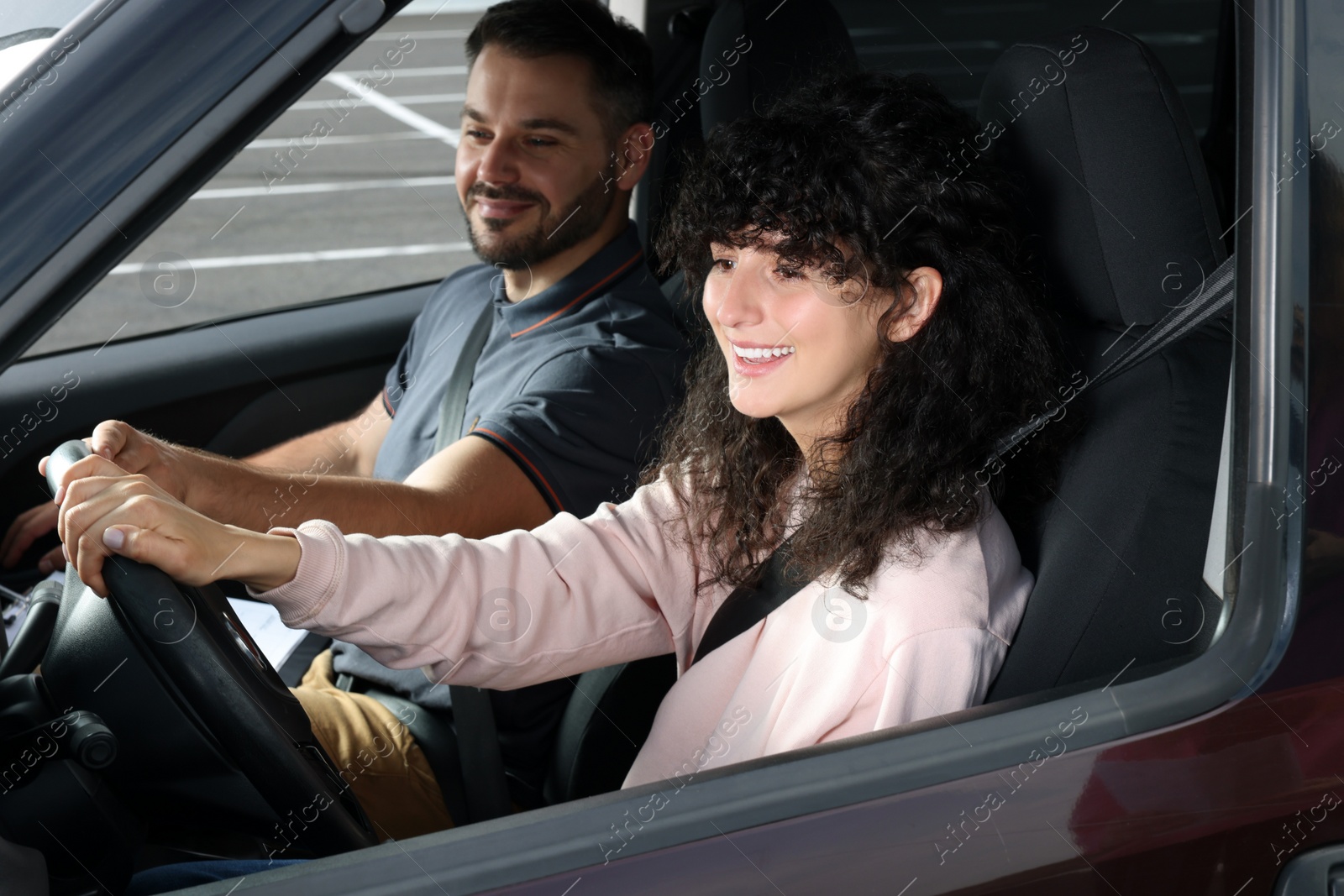 Photo of Driving school. Happy student passing driving test with examiner in car at parking lot