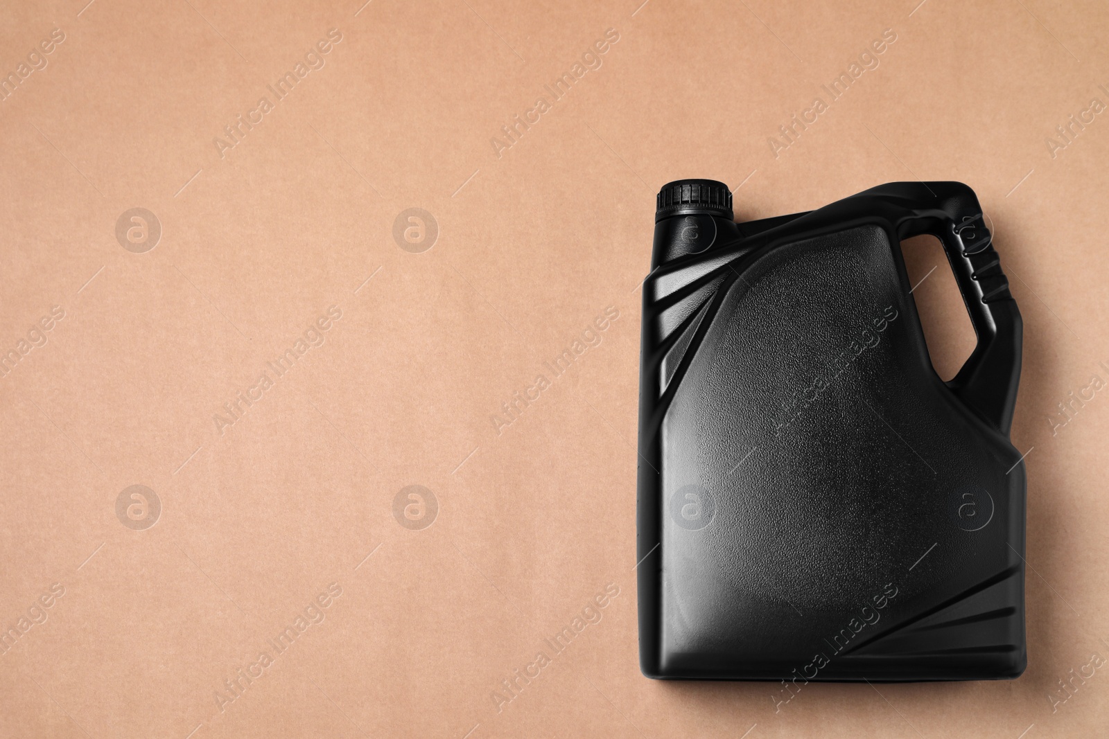 Photo of Motor oil in black canister on light brown background, top view. Space for text