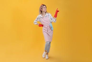 Photo of Young housewife in gloves on yellow background