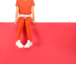 Woman wearing red tights and stylish shoes sitting on color background, closeup. Space for text