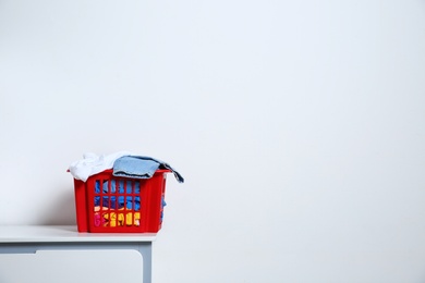 Photo of Laundry basket with dirty clothes on cabinet at white wall, space for text