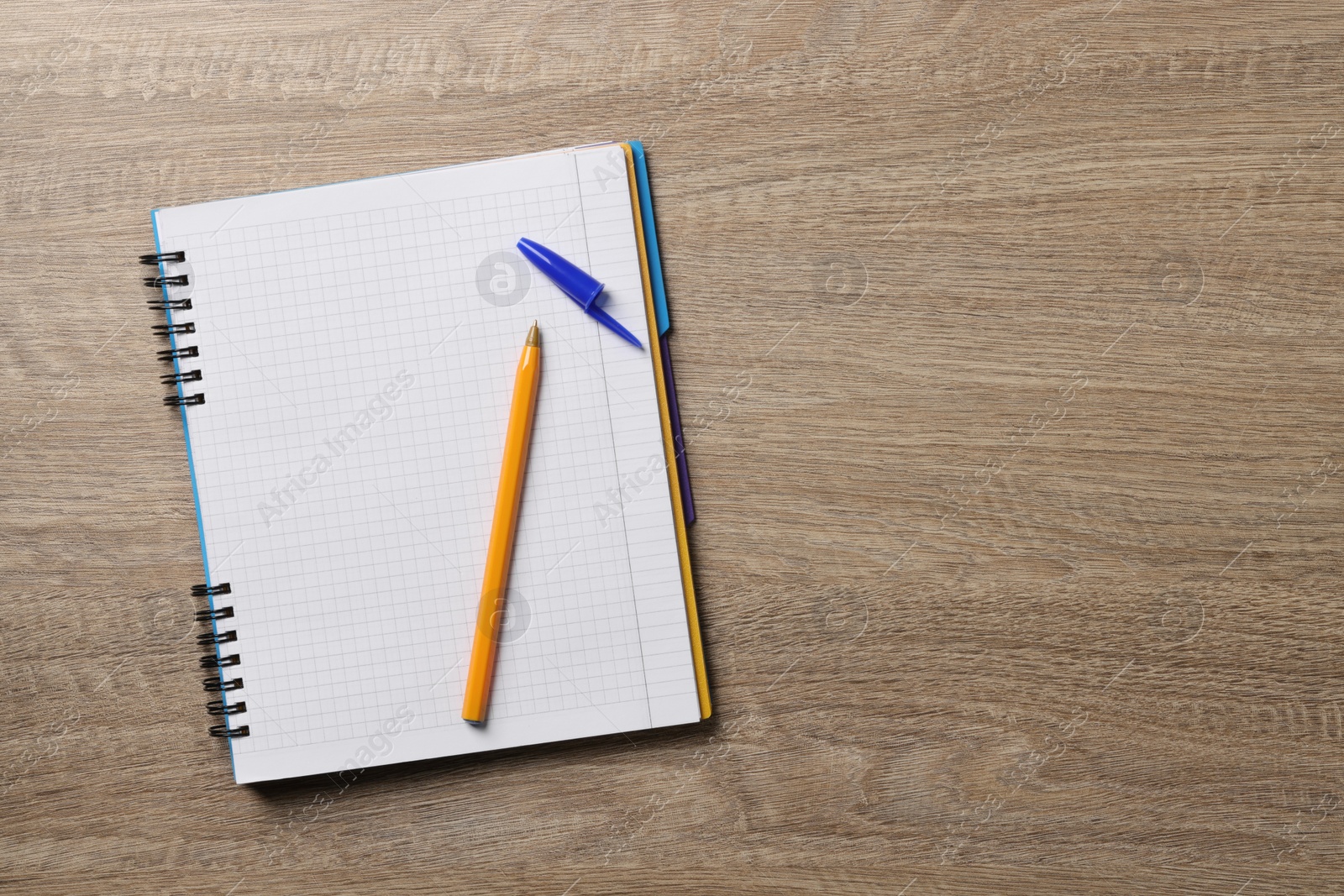 Photo of Ballpoint pen and notebook on wooden table, top view. Space for text