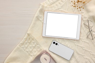 Modern tablet, glasses, smartphone and sweater on white wooden table, flat lay. Space for text