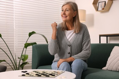 Happy senior woman enjoying winning after playing checkers at home