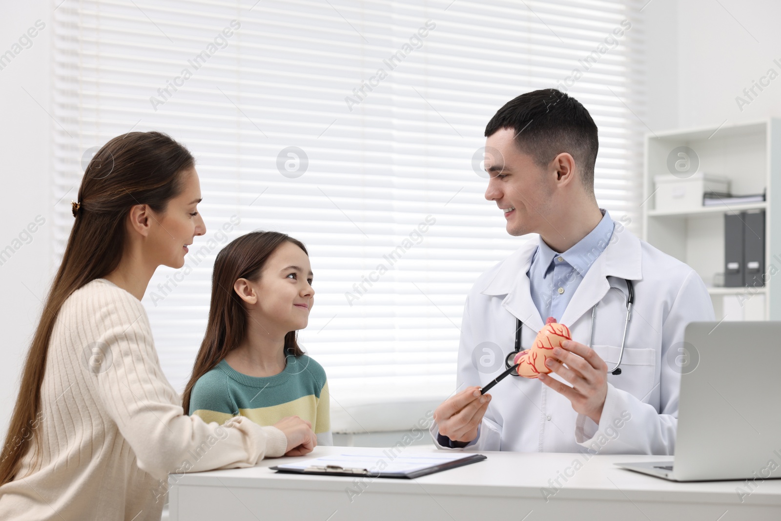 Photo of Gastroenterologist with model of stomach consulting woman and her daughter in clinic