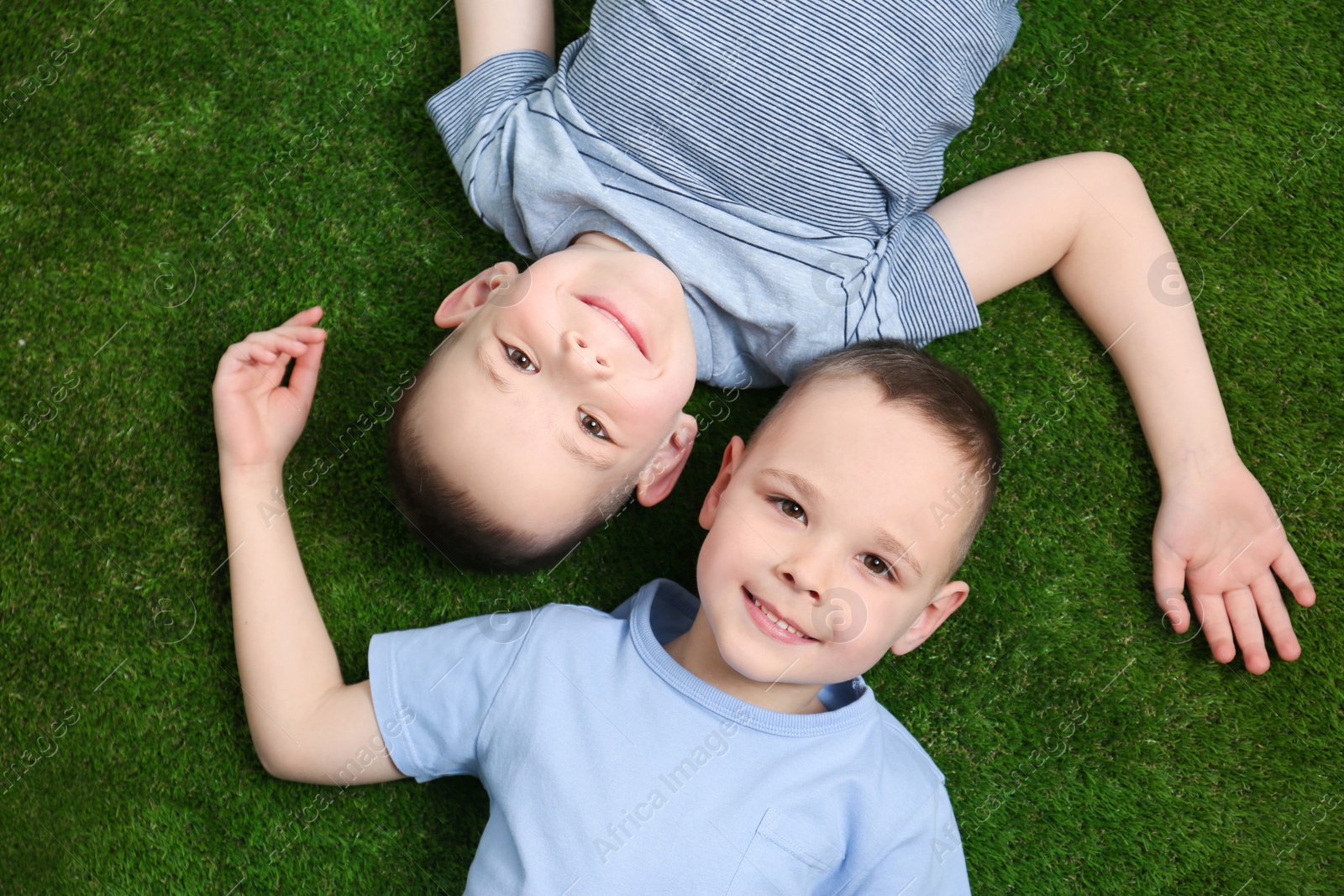 Photo of Portrait of cute twin brothers on green grass, top view