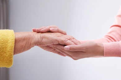 People holding hands together indoors. Help and elderly care service