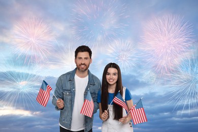 Image of 4th of July - Independence day of America. Happy father and his daughter holding national flags of United States against sky with fireworks