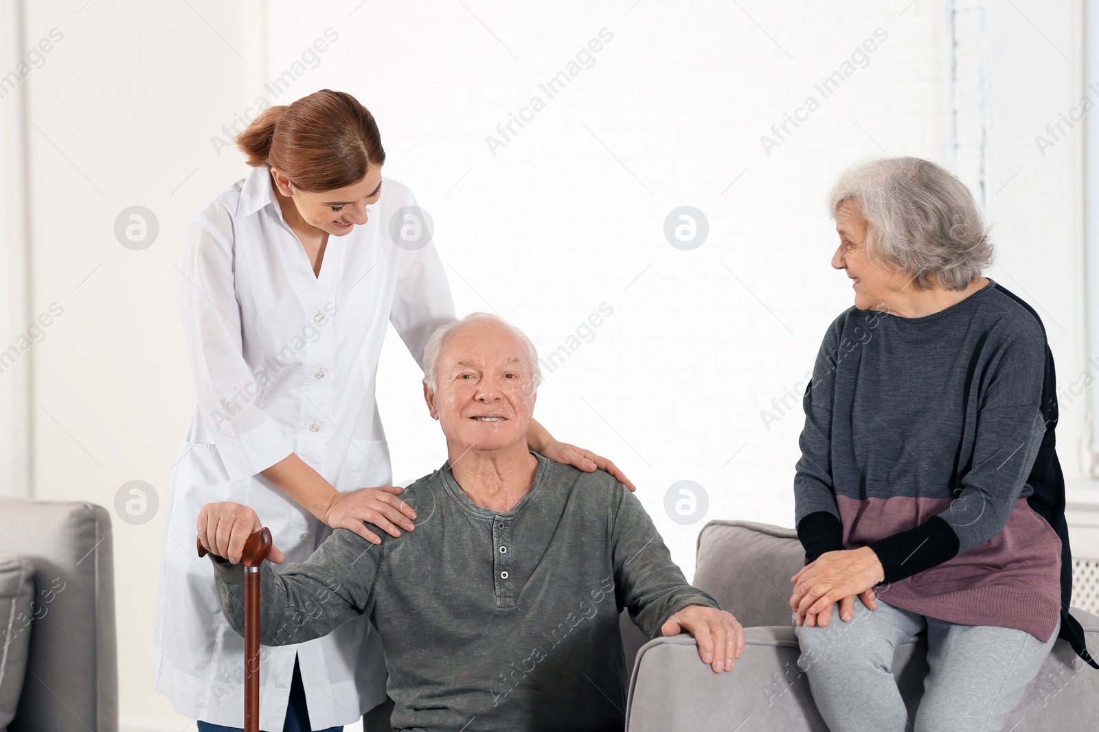 Photo of Elderly spouses with female caregiver in living room