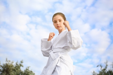 Photo of Cute little girl in kimono training karate outdoors