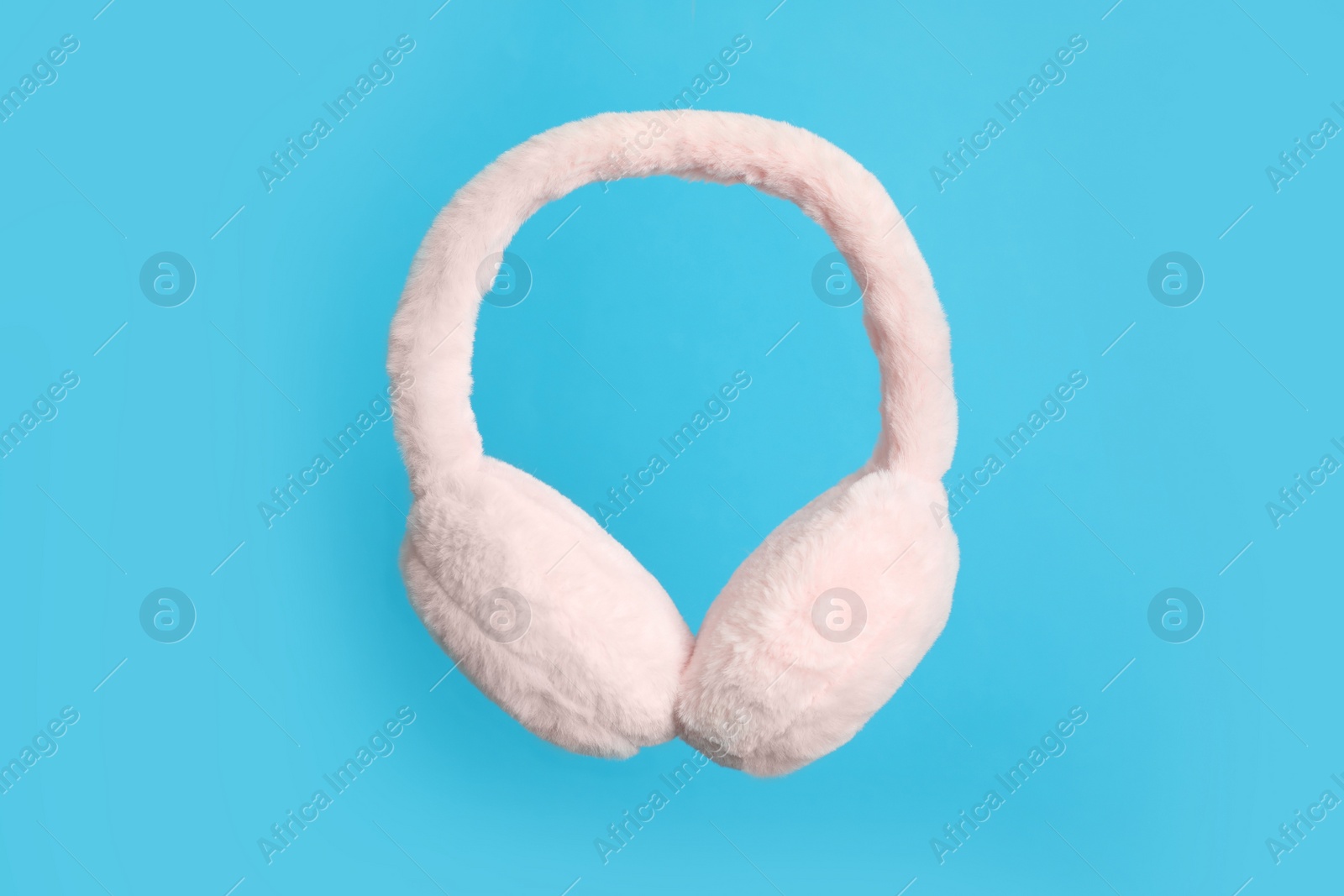 Photo of Stylish winter earmuffs on light blue background