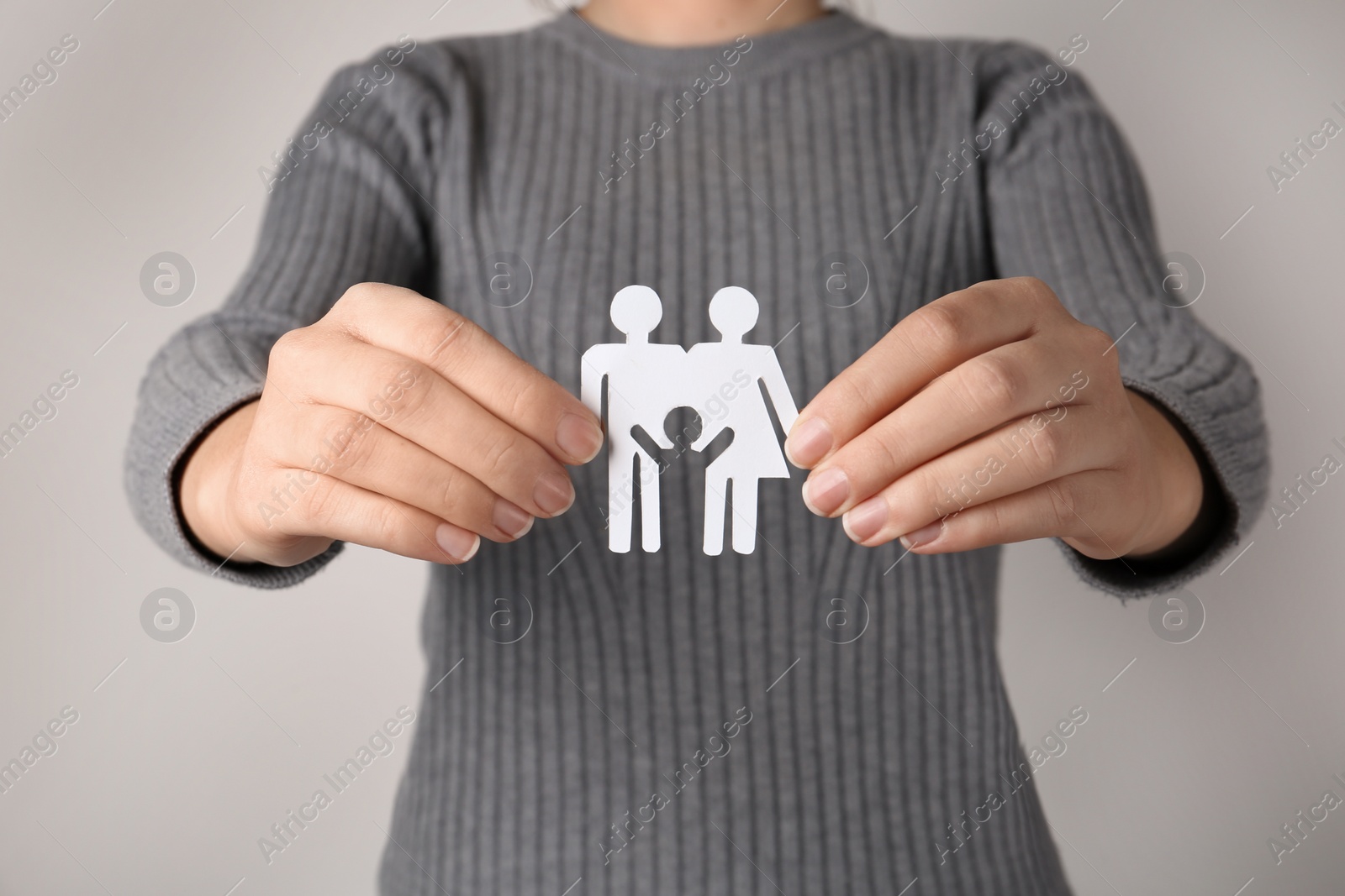 Photo of Woman holding paper silhouette of family on grey background, closeup. Life insurance concept