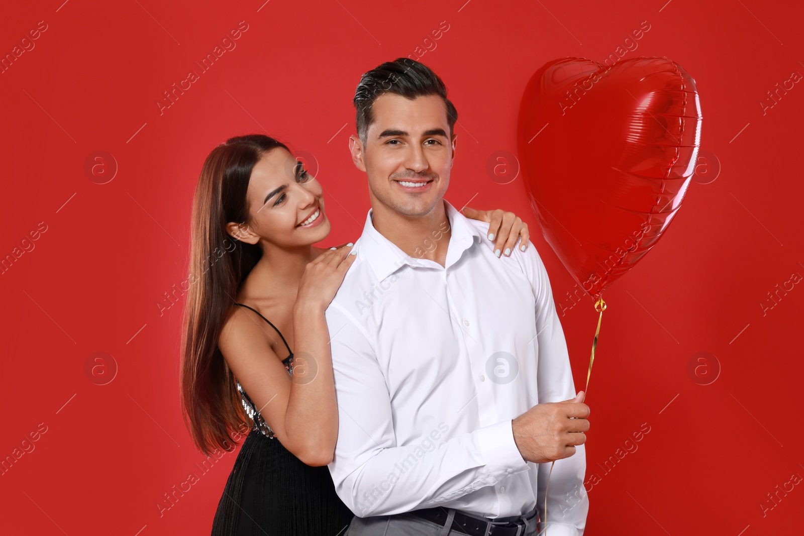 Photo of Beautiful couple with heart shaped balloon on red background