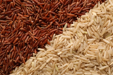 Photo of Different types of brown rice as background, top view