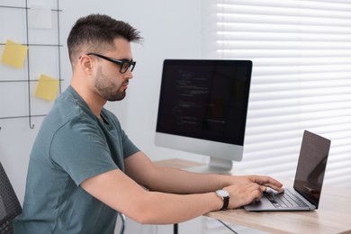 Photo of Young programmer working at desk in office