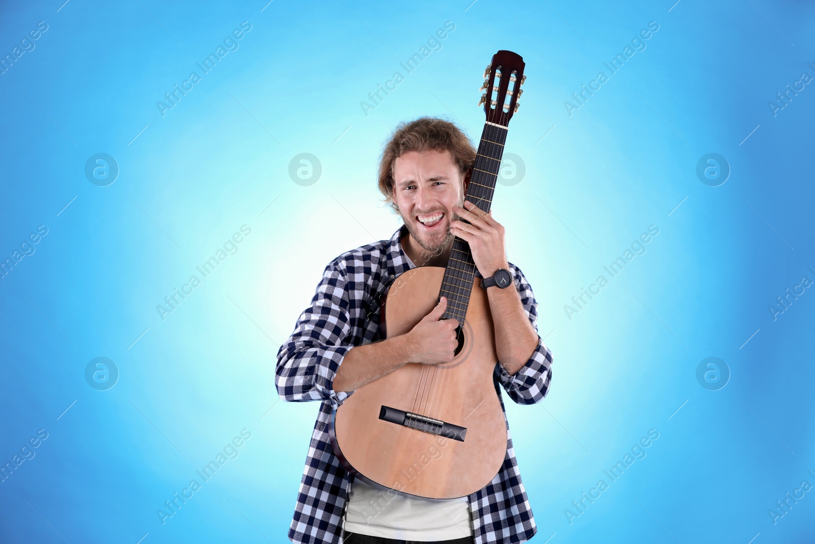 Photo of Young man with acoustic guitar on color background