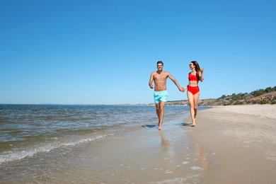Photo of Woman in bikini and her boyfriend on beach, space for text. Happy couple