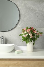 Photo of Vase with beautiful Alstroemeria flowers near sink in bathroom