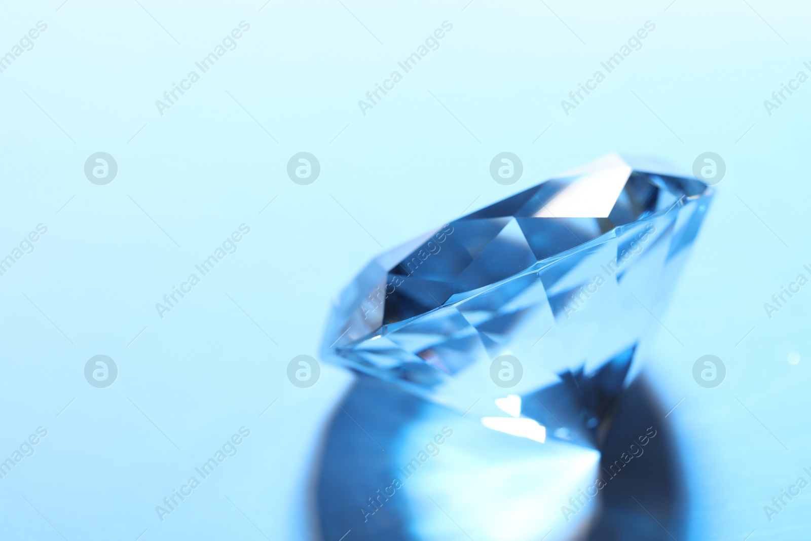 Photo of Beautiful dazzling diamond on blue background, closeup. Space for text