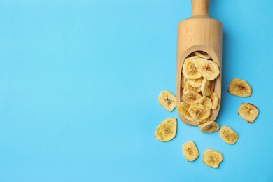 Photo of Wooden scoop with banana slices on color background, top view with space for text. Dried fruit as healthy snack