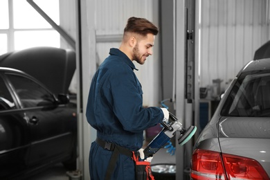 Photo of Technician polishing car body with tool at automobile repair shop