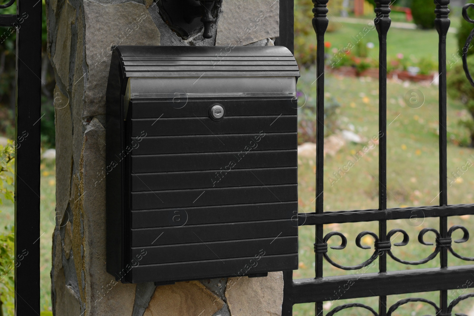 Photo of Metal letter box on stone column near fence outdoors