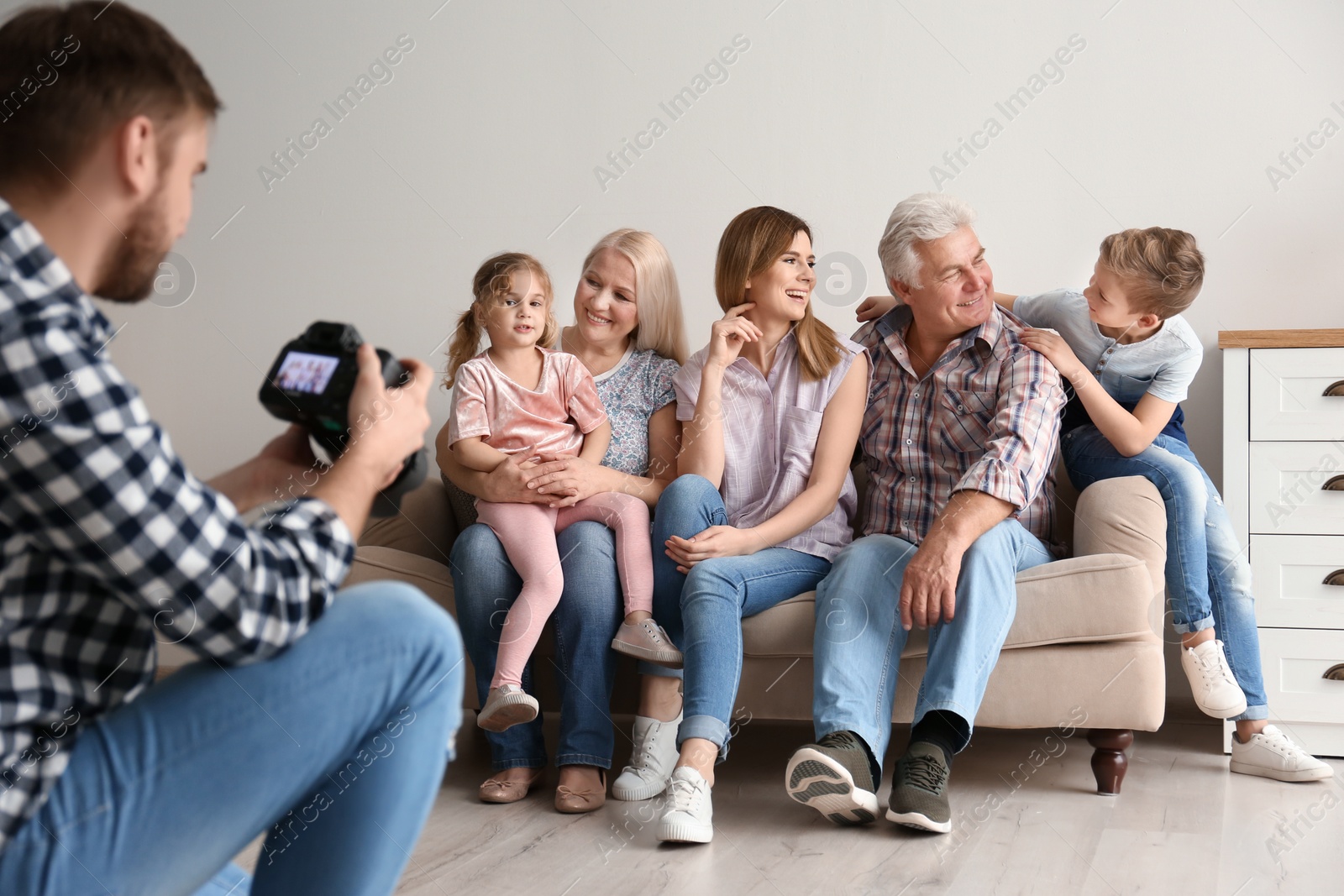 Photo of Professional photographer taking photo of family on sofa in studio