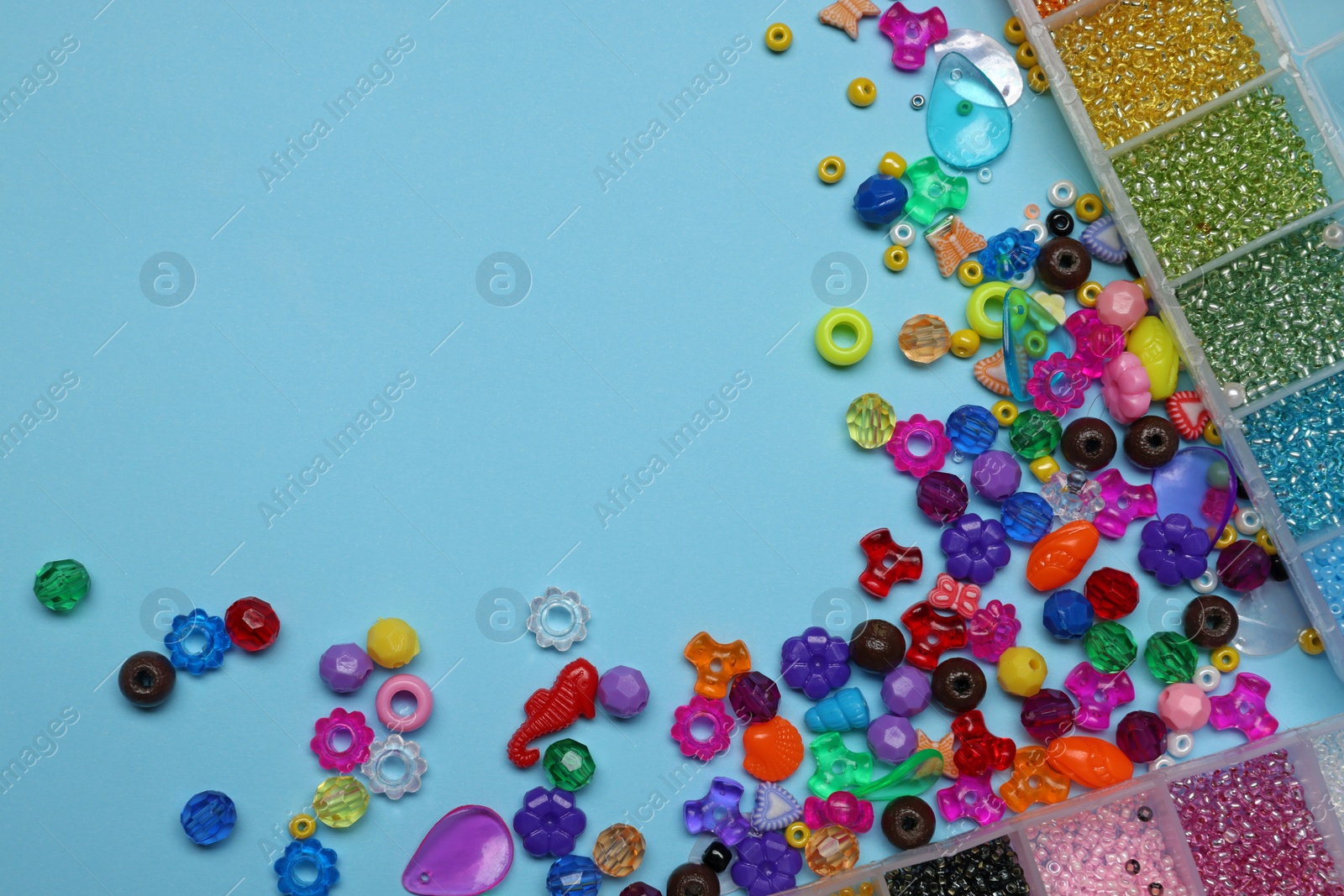 Photo of Flat lay composition with different colorful beads on light blue background, space for text