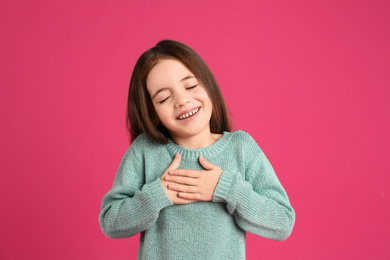 Portrait of cute little girl on pink background