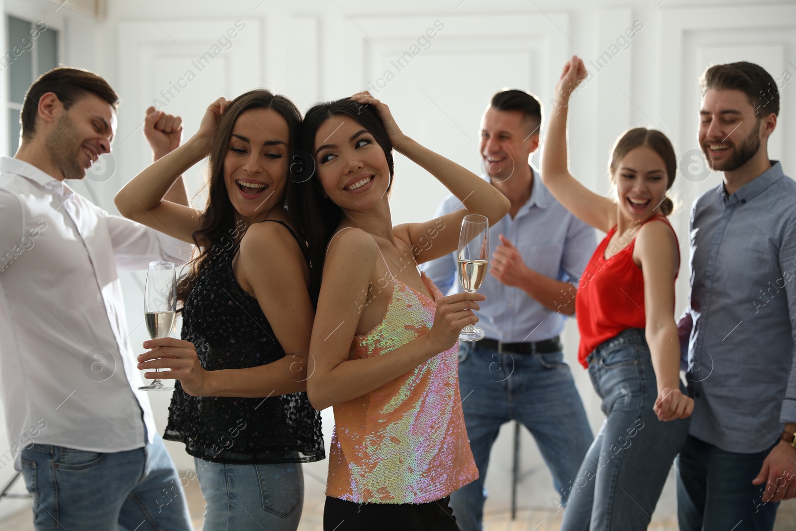 Photo of Couple of happy friends with champagne dancing at party